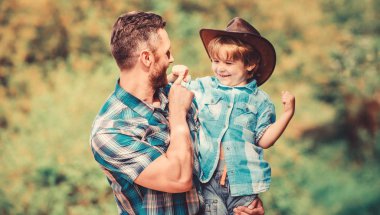 Bahçede küçük bir yardımcı. Küçük çocuk ve baba doğa arka plan. Macera ruhu. Babam gibi güçlü. Güç baba olmak. Çocuk eğleniyor kovboy baba. Rustik bir aile. Büyüyen sevimli kovboy
