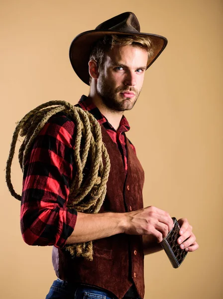 wet your whistle. wild west rodeo. man in hat drink whiskey. man checkered shirt on ranch. western cowboy portrait. Vintage style man. Wild West retro cowboy. cowboy with lasso rope. Western