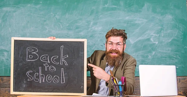 Welcome back. Teacher or school principal welcomes with blackboard inscription back to school. Beginning of new school year in september. Teacher welcomes new pupils to enter educational institution