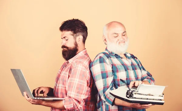 two bearded men. Vintage typewriter. technology generation battle. Modern life. father and son. technology development and improvement. retro typewriter vs laptop. youth vs old age. business approach