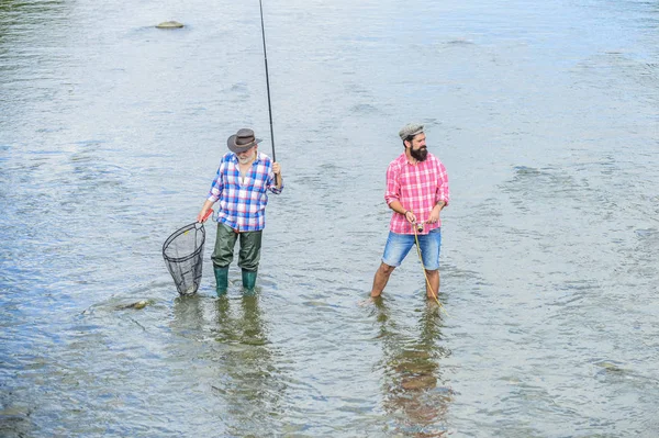 Jag tar fram det bästa. Sommarhelgen. mogna män fiskare. far och son fiskar. två glada fiskare med fiskespö och nät. manlig vänskap. Familjeband. hobby- och idrottsverksamhet. Öringbete — Stockfoto