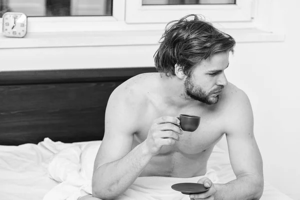 Cada mañana con su café. Empieza bien el día. Cómo el café afecta su cuerpo desde el primer sorbo. Hombre guapo macho con torso muscular relajándose en la cama con taza de café. El café te llena de energía — Foto de Stock