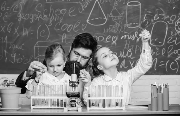 Докажи это. Маленькие девочки проводят эксперименты под наблюдением учителя. Маленькие школьники держат пробирки для лабораторного эксперимента. Демонстрация и эксперимент — стоковое фото
