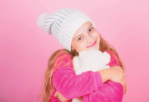 Kid cute girl play with soft toy teddy bear pink background. Child small girl playful hold teddy bear plush toy. Unique attachments to stuffed animals. Teddy bears improve psychological wellbeing