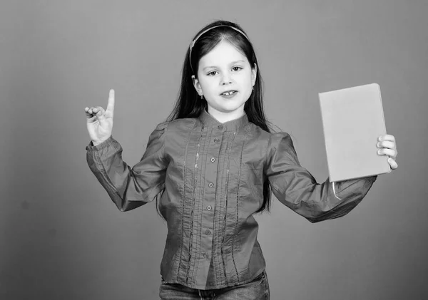 Une idée géniale. Adorable petit enfant tenant le livre d'idées et gardant le doigt levé. Petite fille mignonne se faire une idée du livre. Que le cerveau soit plein de l'idée, copier l'espace — Photo