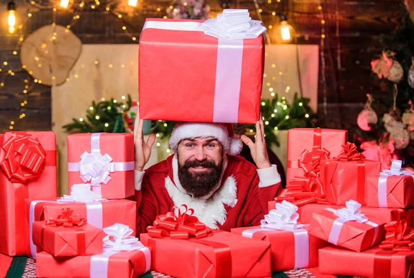 Santa with gifts. Seasonal offer. Christmas sale. Holidays filled with fun. Best prices for winter gifts. Man Santa hat peeking out of pile of gifts. Bearded Santa Claus and many holiday packages