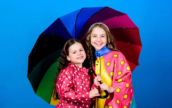 명랑 한 어린이, 자매. 가을 패션. 화려 한 우산을 두른 행복 한 어린 소녀들. 비를 막아주는 장치. 레인보우. 가족의 유대. 비옷입은 여자 애들. 같이 미쳐 가고 있어 — 스톡 사진