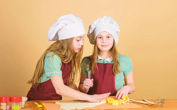 Pişirme tarifi aşağıdaki genç fırıncılar. Mutfak masasına macun yuvarlanan küçük fırıncılar. Fırıncıdükkanında kurabiye pişiren küçük kızlar. Fırıncı unu ile hamur yoğurma