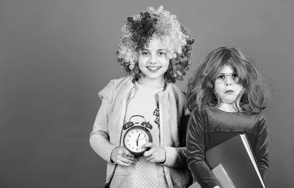 Are we in time. Adorable party goers. Cute children with fancy hair waiting for party time with clock. Little girls wearing crazy wigs going to party night. Party celebration, copy space