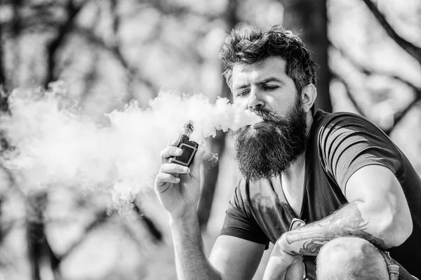 Bearded man smokes vape, white clouds of smoke. Electronic cigarette  concept. Man with long beard looks relaxed. Man with beard and mustache on  calm face, dark background, defocused Stock Photo by ©stetsik
