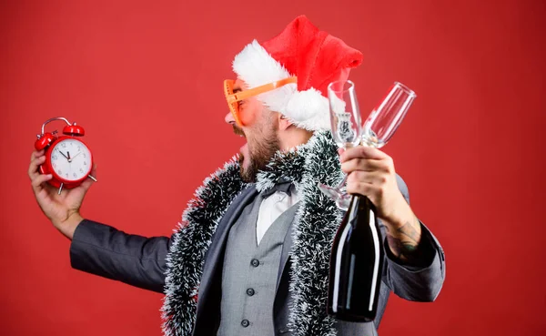 Join office party. Winter party ideas. Almost midnight. Time to celebrate new year. Christmas party. Man bearded hipster santa hat champagne bottle. alarm clock. Corporate party. Cheers concept