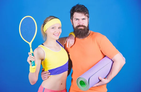 Unis nous jouons. Unis nous gagnons. Muscles forts et corps. Femme heureuse et homme barbu séance d'entraînement dans la salle de gym. Équipement sportif. Entraînement sportif en couple avec tapis de fitness et raquette de tennis. Succès sportif — Photo