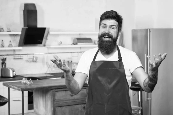 Cocinar en cocina nueva. Necesito inspiración culinaria. El fin de semana comienza con un delicioso desayuno. Cómo convertir la cocina en casa en hábito. Hombre barbudo delantal hipster rojo de pie en la cocina. Tienda de muebles de cocina —  Fotos de Stock