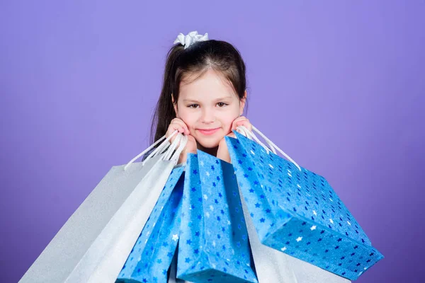 Venta día de los niños. Moda infantil. asistente de tienda con paquete. oferta especial. Ahorro de compra vacaciones. Feliz niña. Niña con regalos. Ventas y descuentos. Niña con bolsas de compras —  Fotos de Stock