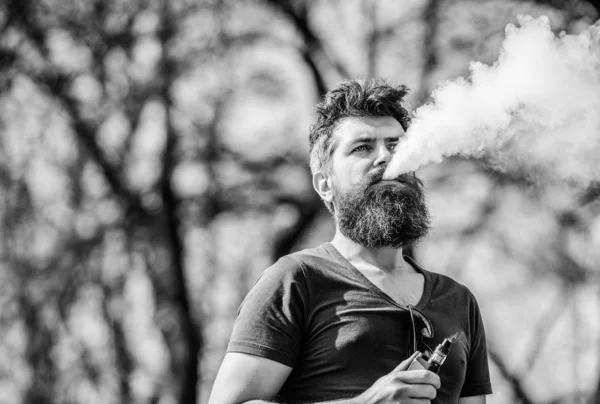 Conceito de alívio de estresse. Homem barbudo a fumar vape. Fumar cigarro electrónico. Homem barba longa relaxado com hábito de fumar. Homem com barba e bigode exala fumo. Nuvens brancas de fumaça aromatizada — Fotografia de Stock