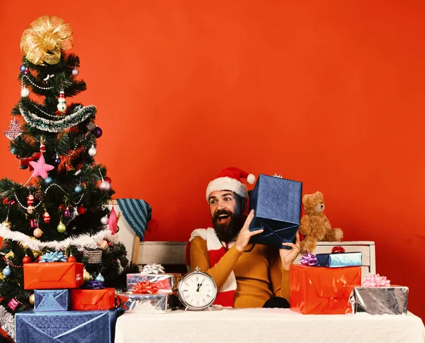 Père Noël ouvre cadeaux près de l'arbre décoré sur fond rouge — Photo