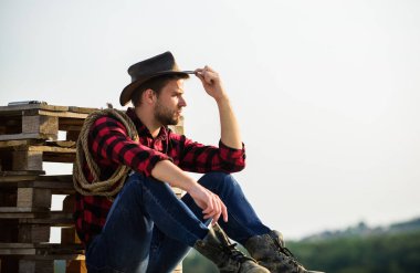 Gerçek bir kovboy. Klasik tarz adam. Vahşi Batı eski kovboy. Vahşi batı rodeosu. Şapkalı düşünceli adam rahatla. Çiftlikte kareli gömlek. Kement ipli bir kovboy. Batı. Batı kovboy portresi