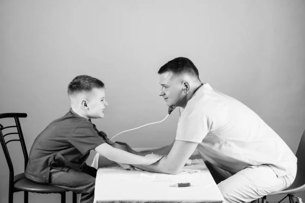 professional talk. medicine and health. small boy with dad play. Future career. nurse laboratory assistant. family doctor. happy child with father with stethoscope. father and son in medical uniform