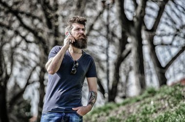 Sakallı adam cep telefonunu arıyor. İletişim konsepti. Sonra ara. Yönlendirilmiş arama. Mesajı dinliyorum. Şu anda müsait değil. Cep telefonu kullanan sakallı bir hippi. Sakallı adam arıyor.