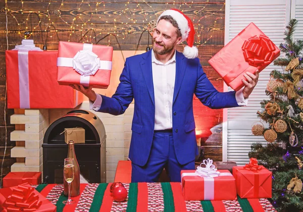 Man prepared gifts for everyone. Spread happiness and joy. Generosity concept. Gifts for colleagues. Which one is mine. Man bearded businessman wear suit santa hat hold gift boxes. Christmas gifts