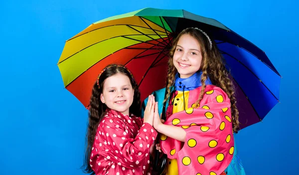 Happy childhood. Bright umbrella. It is easier to be happy together. Be rainbow in someones cloud. Walk under umbrella. Kids girls happy friends under umbrella. Rainy weather with proper garments