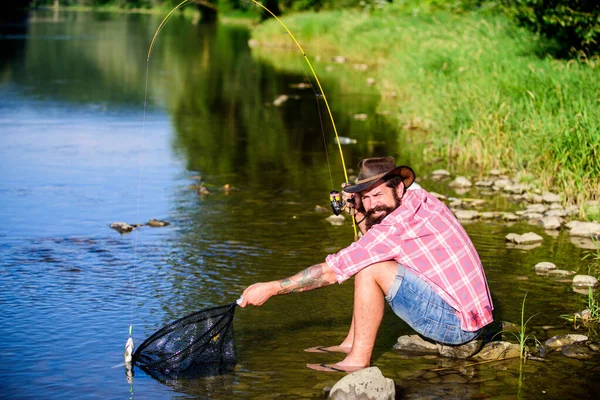 Хобби для души. Человек на берегу реки наслаждаться мирным идиллическим ландшафтом во время рыбалки. Объединились с природой. Рыбак рыбалка технику использовать стержень. Человек ловит рыбу. Мужик рыбачит. Успешная рыбалка — стоковое фото