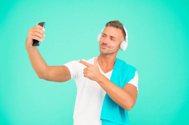 El resmi. Yakışıklı adam akıllı telefondaki selfie kamerasını işaret ediyor. Gülümseyen mutlu sporcu cep telefonuyla selfie çek. Eğitimden sonra selfie çekmenin tadını çıkarıyorum.