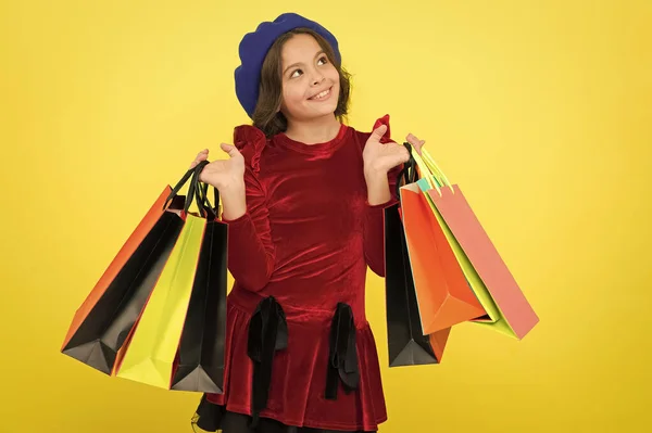 Niña sostenga manojo bolsas de compras o paquetes de regalos de cumpleaños. Concepto de compras de cumpleaños. Niño linda niña pequeña en gira de compras. El mejor precio. Compra ahora. Visita el centro comercial. Todo lo que quiero para mi cumpleaños —  Fotos de Stock