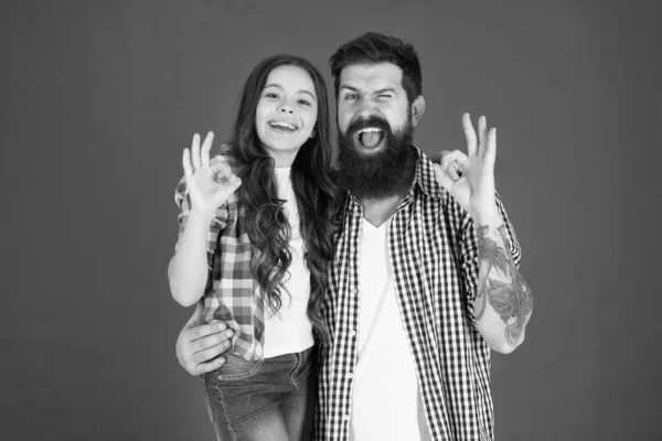 Father and daughter hug on red background. Child and father best friends. Parenthood goals. Happy childhood. Fathers day concept. Lovely bearded dad and cute kid. Cheerful family. Happy fathers day