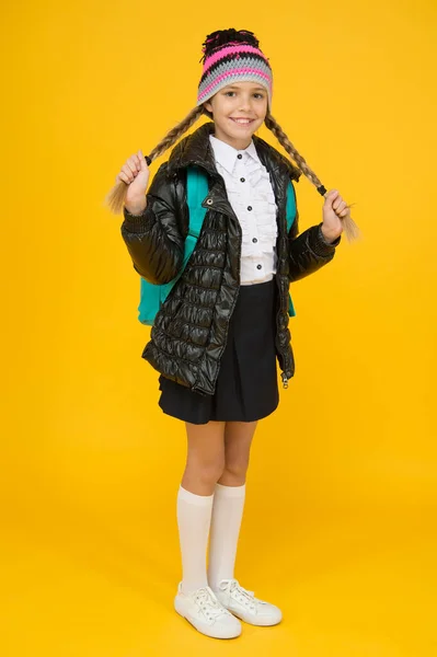Fashion concept. Warm clothing. Buy clothes for school season. Schoolgirl fashion outfit. Fall autumn winter. Child with backpack. Fashion shop. Girl wear knitted hat and jacket yellow background — Stock fotografie