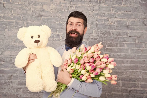 Wow. Love date. international holiday. Spring gift. Bearded man hipster with flowers. Bearded man with tulip bouquet and bear. Flower for March 8. Womens day. Natural beauty. Capturing a happy moment — Stock Photo, Image