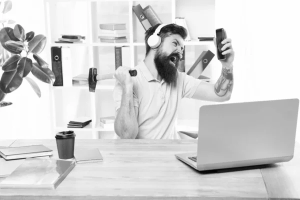 Incoming call. Most annoying thing about work in call center. Annoying client calling. Man bearded guy headphones office swing hammer on smartphone. Spoiled communication. Failed mobile negotiations