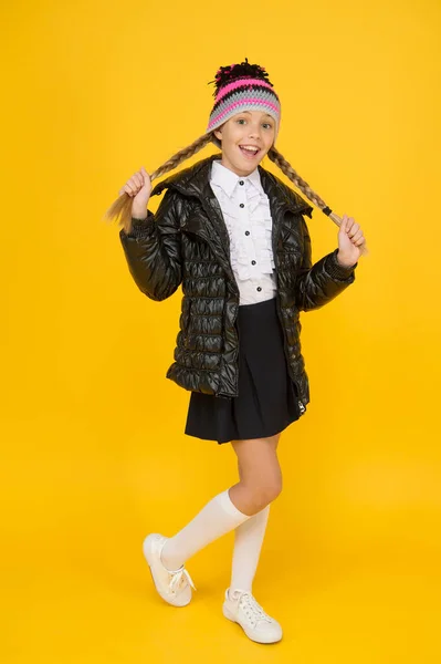 Des vêtements chauds. Achetez des vêtements pour la saison scolaire. Tenue de mode écolière. Automne automne hiver. Charmant petit enfant. Boutique de mode. Fille porter chapeau tricoté et veste en duvet fond jaune. Concept de mode — Photo