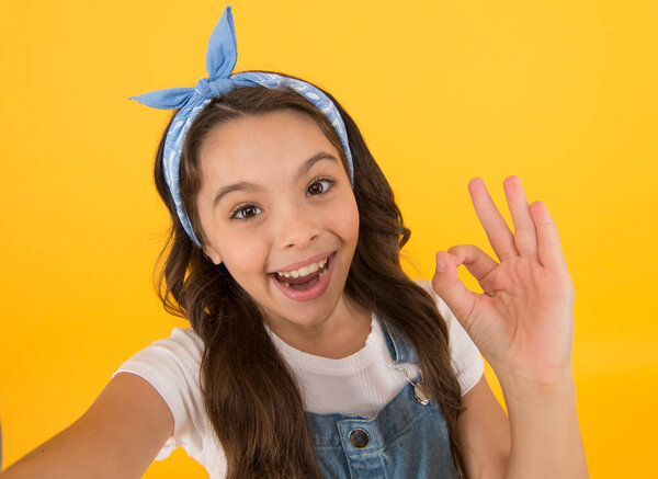 Its ok. Happy little child with ok hand on yellow background. Small girl smiling with ok gesture. Ok sign. Nonverbal language communication