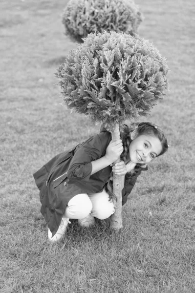 Spring fashion for little girl. Happy child with thuja. Nature landscape design. Parks and outdoor. Autumn weather. Cypress tree. Little girl with trendy hairstyle. Hello spring. Enjoying autumn day