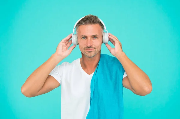 Ejercicio de música. Hombre guapo disfrutar de la música sobre fondo azul. El atlético escucha música en los auriculares. Escuchar música mejora tu entrenamiento. Entrenamiento en gimnasio — Foto de Stock