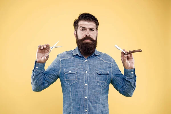 Um estilista pessoal. Um barbeiro vintage. Homem barbudo segura navalha e tesoura. Barbearia retro. Hipster com ferramentas antigas. A desenhar corte de cabelo. Penteado fresco. Conceito de barbearia. Cuidar dos homens. Salão de barbearia — Fotografia de Stock