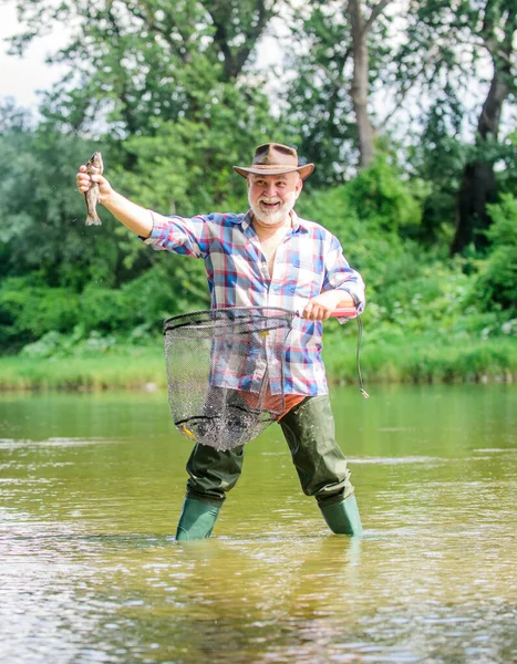 Hobby sport activity. Pensioner leisure. Fish farming pisciculture raising fish commercially. Fisherman fishing equipment. Fisherman alone stand in river water. Man senior bearded fisherman