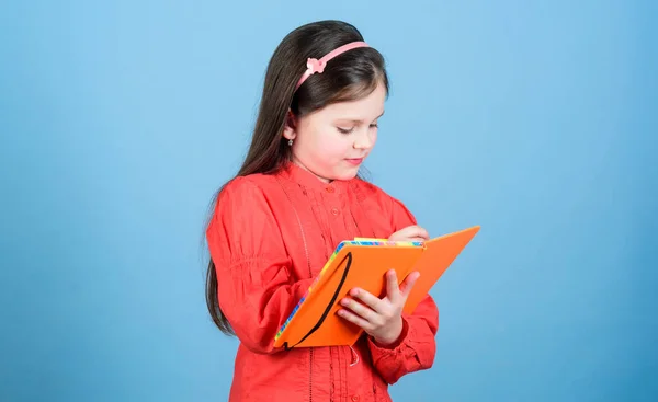 소녀는 파란 배경 책을 가지고 있습니다. 아이가 책을 쓰고 있어요. 책 컨셉. 개발 과 교육. 숙제를 한다. 작곡. 문학 클럽. 개인 일기. 배우고 배우는 것입니다. 시 작가 — 스톡 사진