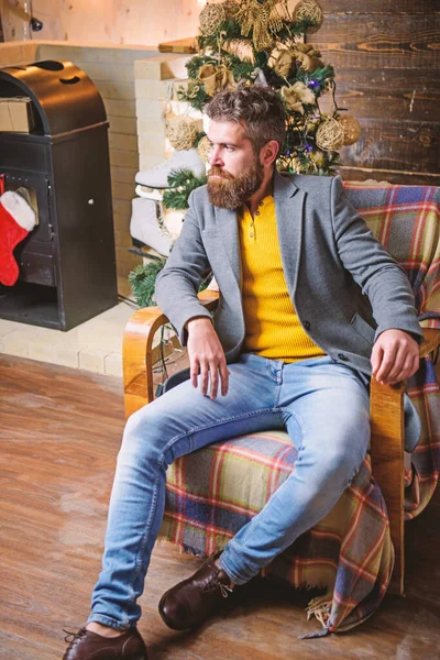 Home is best place. Man bearded hipster relax sit armchair near christmas tree. Feel like home. Man mature confident guy with beard relax at home. Warm and cozy christmas atmosphere at home