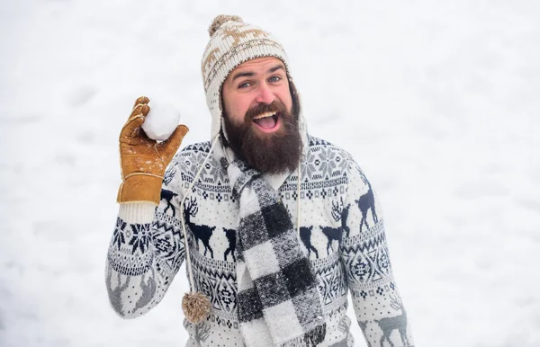 Homme souriant fond de neige. Jeux de neige. Amusez-vous bien. Joyeux chapeau barbu tricoté hipster et gants chauds jouent avec la neige à l'extérieur. Vacances de Noël. Faire de la boule de neige. Concept de bonheur — Photo