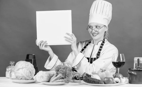 Culinary school concept. Female in hat and apron knows everything about culinary arts. Traditional cuisine. Culinary expert. Woman chef cooking healthy food. Girl read book top best culinary recipes