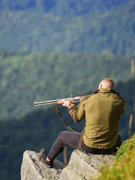 Hunter spend leisure hunting. Man brutal gamekeeper nature landscape background. Hunting in mountains. Hunting masculine hobby concept. Regulation of hunting. Focused on target. Hunter hold rifle