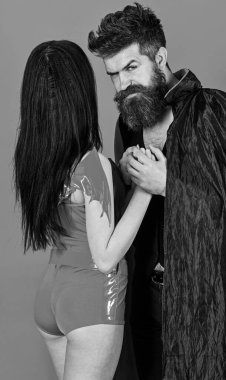 Cadılar Bayramı konsepti. Sıkı yüz oyun rol oyunu çift. Vampir pelerin ve seksi şeytan kız el ele tutuşuyor. Aşık bir çift, mükemmel bir eş. Erkek ve kadın vampir, iblis, kırmızı backgroun gibi giyinmiş