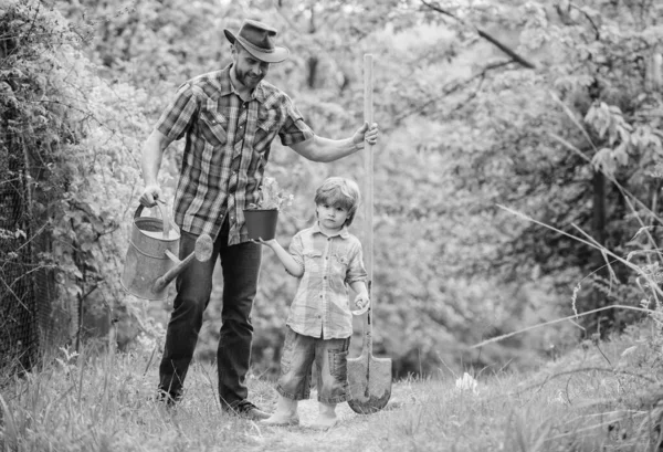 Boldog föld nap. Családi fa nursering. Öko-farm. kisfiú gyermeke segít apja a gazdálkodásban. öntözés, pot és lapát. Kerti felszerelések. apja és fia cowboy kalapban a tanyán. Szerette a kertészetben — Stock Fotó