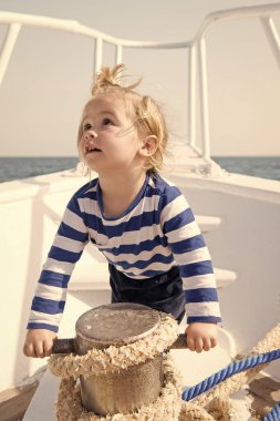 teknede küçük denizci. yattaki mutlu küçük çocuk. deniz veya okyanus tekne gezisi. yaz tatili. Çocukluk. yatçılık sporu. çizgili deniz gömleği giyen çocuk. seyahat maceraları ve wanderlust. Yachting