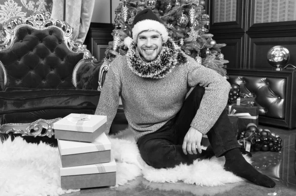 クリスマスの願いが叶います。クリスマス ギフト用の箱で幸せな男。男は、家でクリスマスを祝っています。配信クリスマス プレゼント。サンタの帽子の男は、クリスマス プレゼントを保持します。我々 は与えるこの、たびに、クリスマス — ストック写真