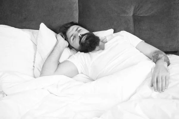 Бессонная ночь. Концепция расстройств сна. У бородатого хипстера проблемы со сном. Парень лежит в постели, пытается расслабиться и заснуть. Методы релаксации. Нарушения сна и бодрствования — стоковое фото