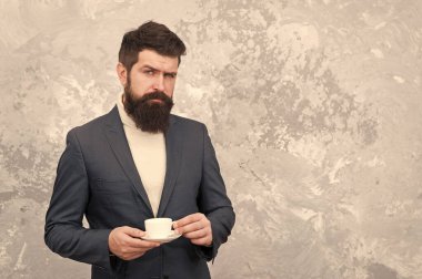 Spesiyal kahve. Yakışıklı sakallı iş adamı elinde bir fincan kahve tutuyor. Kahve molası. İş adamları moda tarzında. Ofis hayatı için şık günlük kıyafetler. Onun için en iyi kahve.