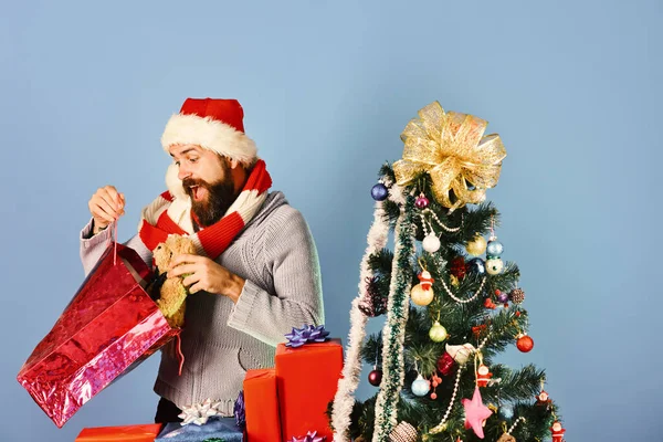 Weihnachtsmann mit roten Geschenken neben geschmücktem Tannenbaum. — Stockfoto